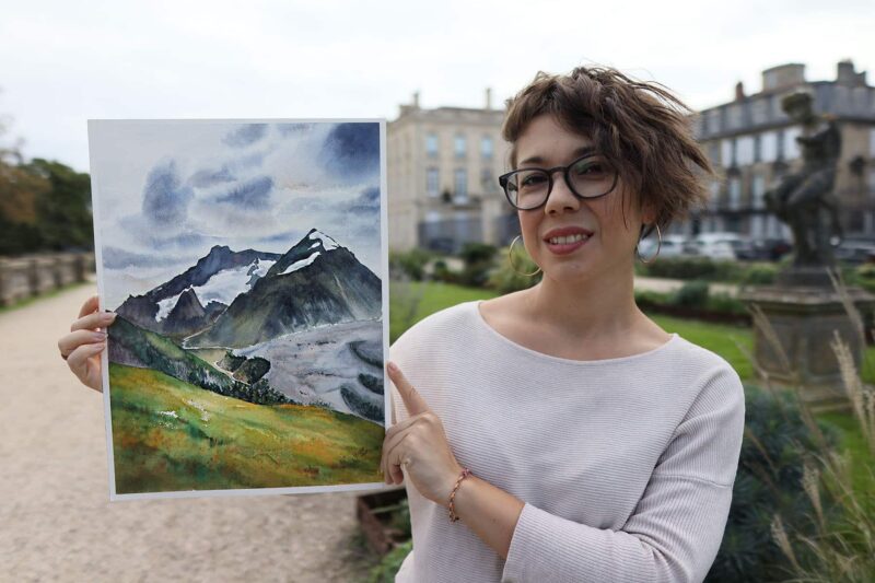 an artist hold a watercolor painting of snowy mont blanc